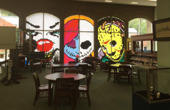 A picture from inside a darkened library with pictures of characters from horror movies on the windows.
