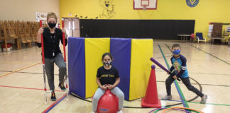 A picture of a woman on stilts, a girl sitting on a bouncing ball and a boy playing with a baseball bat in a gym.