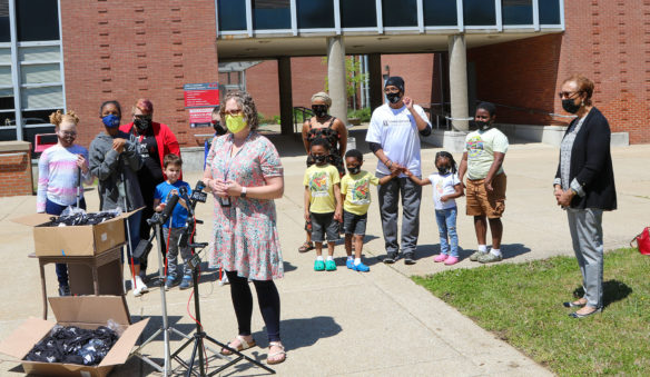 Kentucky School for the Blind Principal Peggy Sinclair-Morris speaks in front of microphones outside of a school building. Several KSB students and other attendees stand behind her.