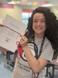 Picture of a smiling woman holding a piece of paper.