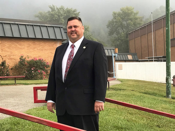 A mean wearing a suit stands in front of a building.