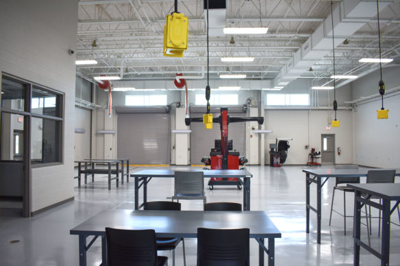 Picture of an empty classroom filled with tables, with cords hanging down over each table.