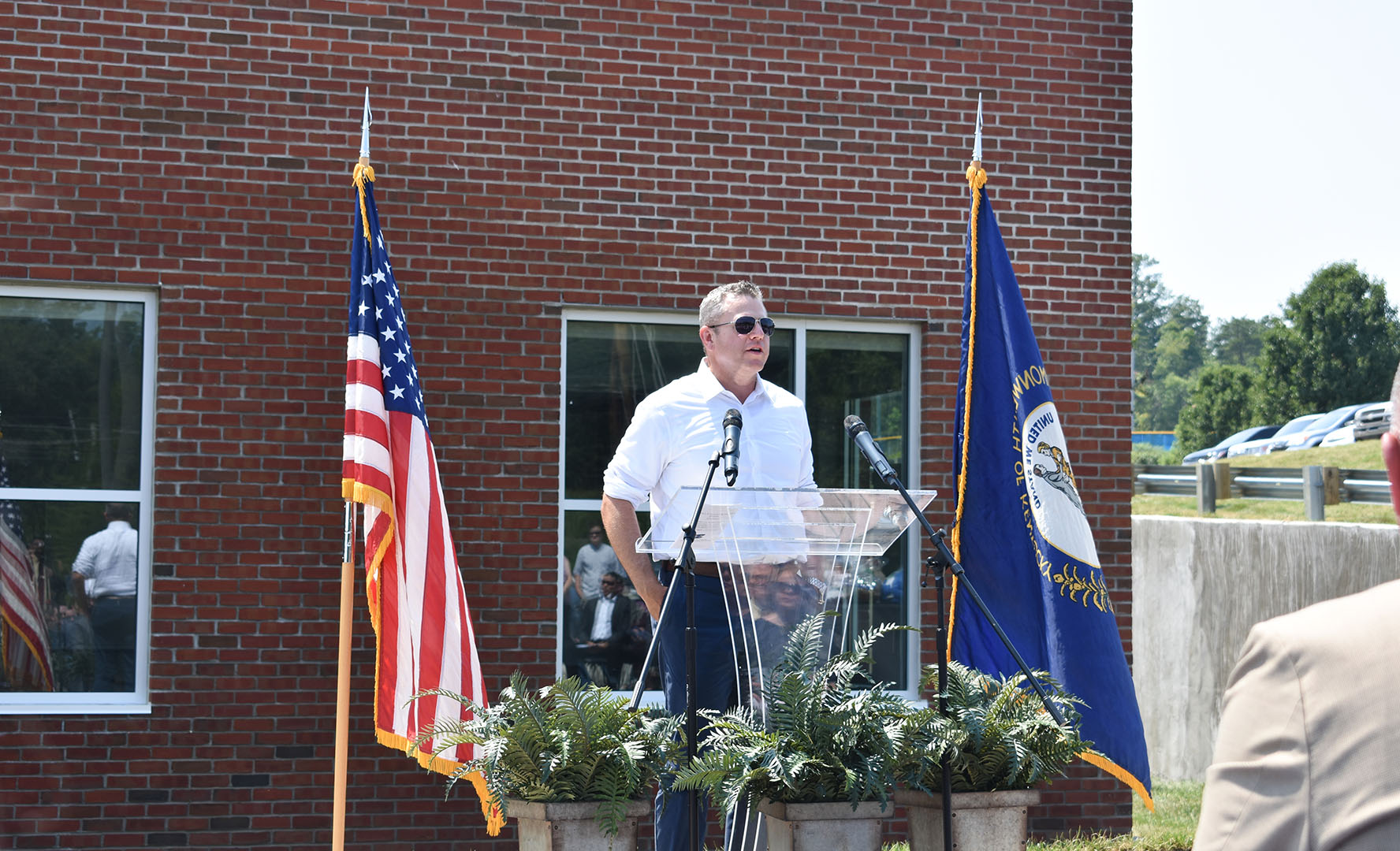 A man stands in front of a building at a podium, speaking.