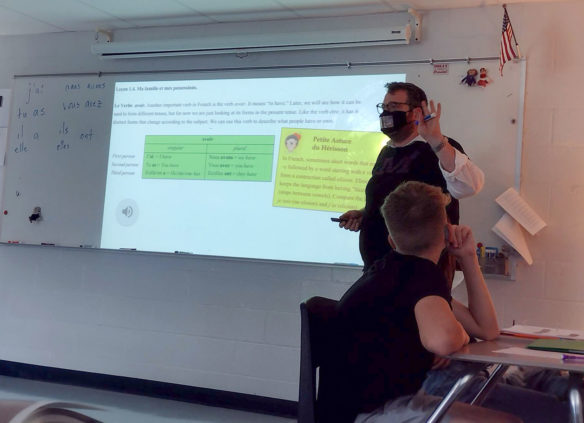 Picture of a man in a darkened room talking to students.