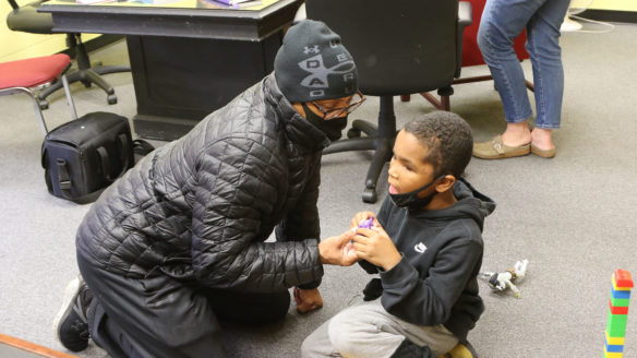 Picture of a man sitting on the floor playing with a young boy.