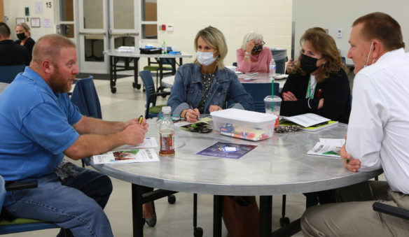 Picture of four people sitting around a school cafeteria table talking.