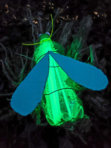 Picture of a firefly made out of a plastic bottle with glow sticks inside of it.