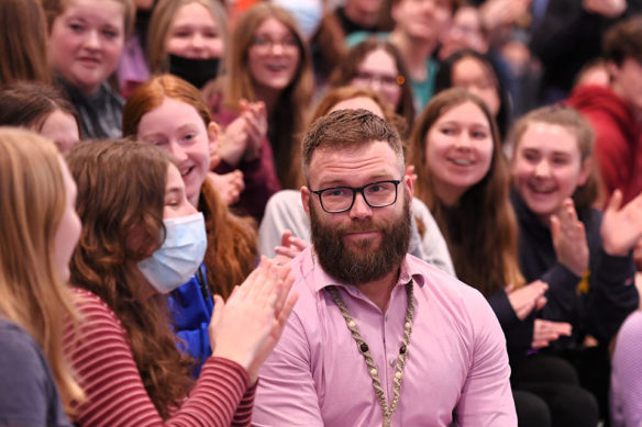 Picture of a man looking surprised, surrounded by students who are smiling and clapping.