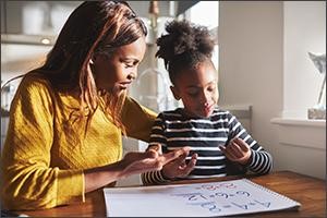 Photo of mother and child working on schoolwork together.