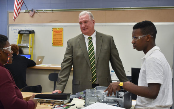 A man stands talking to a student in a classroom. 