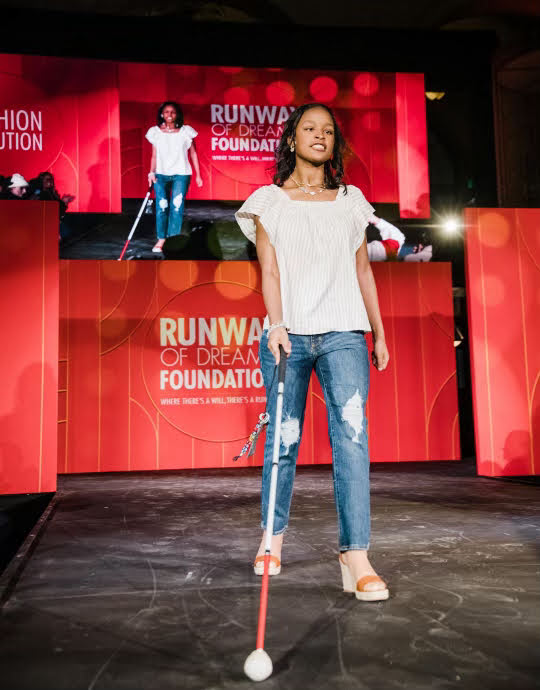 A girl walks on a fashion show runway.