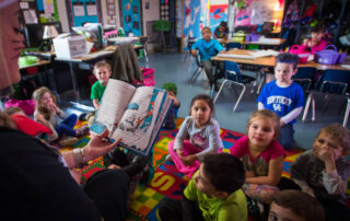 A teacher reads a book to a group of students.