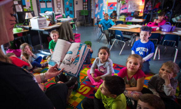A teacher reads a book to a group of students. 
