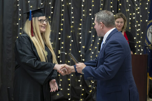 Picture of a young woman shaking the hand of a man wearing a suit.