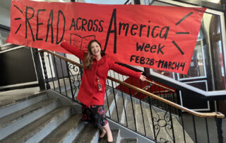 A woman stands in front of a banner that reads: "Read Across America Week"
