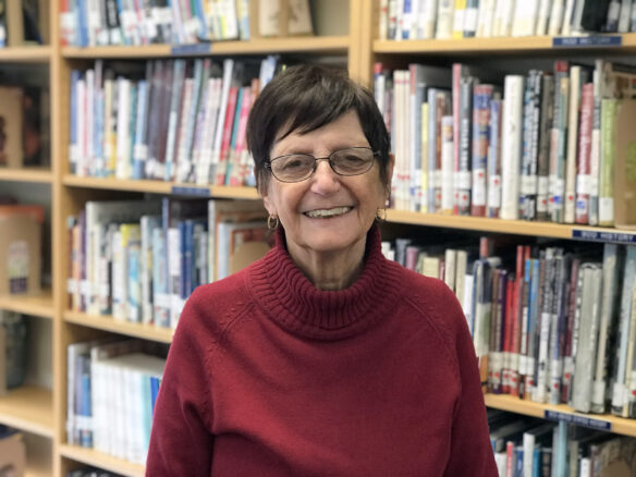 Headshot photo of a woman smiling in front of shelves filled with books. 