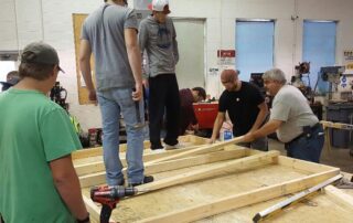 Students standing on a wooden platform arranging pieces of wood.