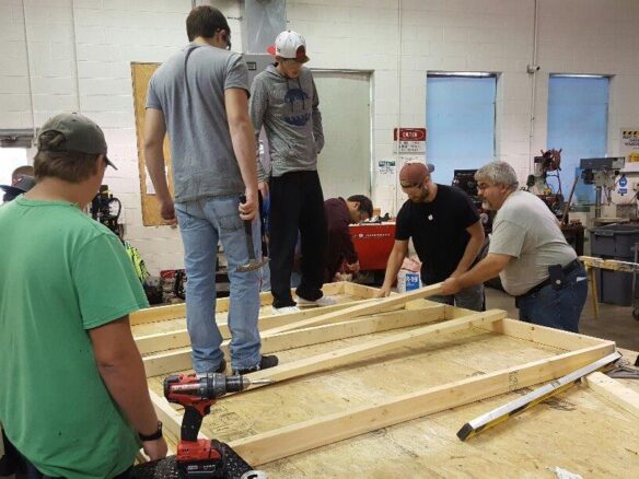 Students standing on a wooden platform arranging pieces of wood.