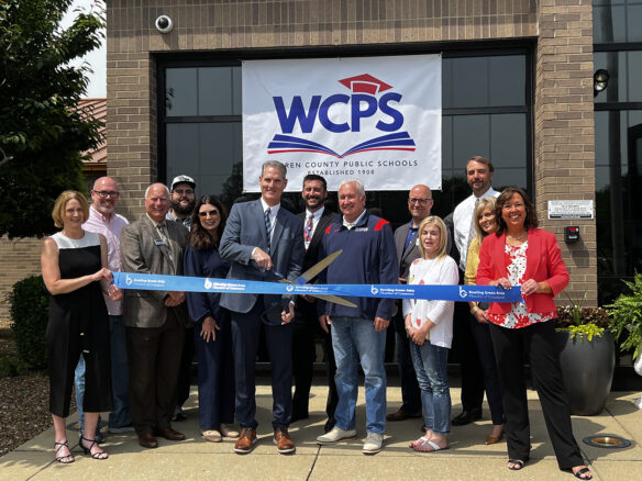 A group of people cutting a ribbon while standing in front of a sign that reads: WCPS.