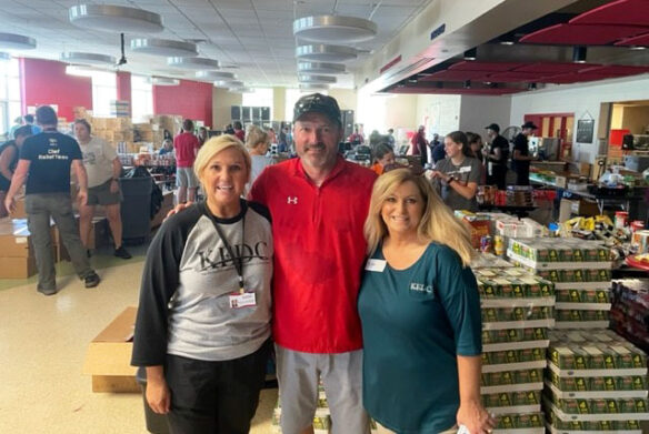 Picture of Nancy Hutchinson, Jonathan Jett and Trish Carroll in a cafeteria filled with donations.