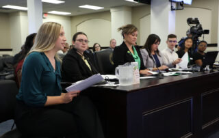 Charleigh Browning and other members of the Commissioner's Student Advisory Council sit at a table speaking at the Kentucky legislature's Interim Joint Committee on Education meeting.