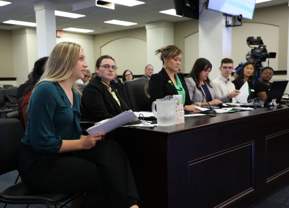 Charleigh Browning and other members of the Commissioner's Student Advisory Council sit at a table speaking at the Kentucky legislature's Interim Joint Committee on Education meeting. 