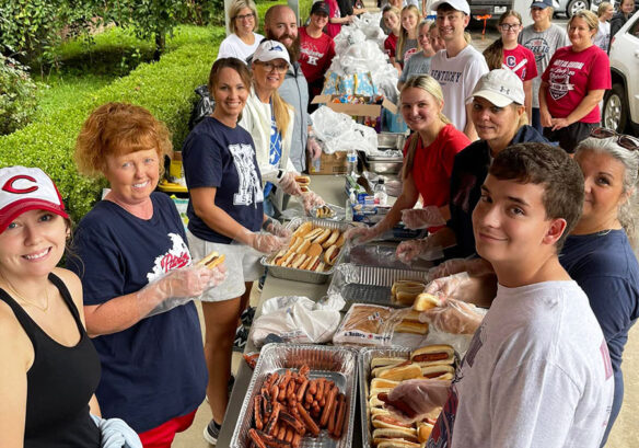 A group of people standing around a long table filled with food.