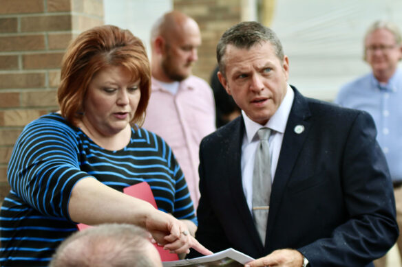 A woman points to a paper the man next to her is holding. 