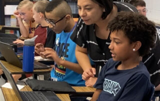 Picture of Mandy Perez looking at a computer over the shoulder of a student in her classroom.