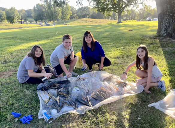 A picture of Kelly Gates sitting under a tree with three young students.