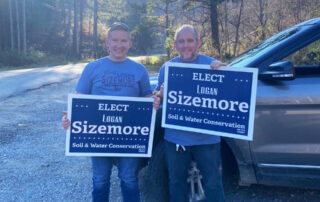 Picture of Logan Sizemore holding an "Elect Logan Sizemore" sign with his uncle, who is holding a similar sign, on election night 2022.