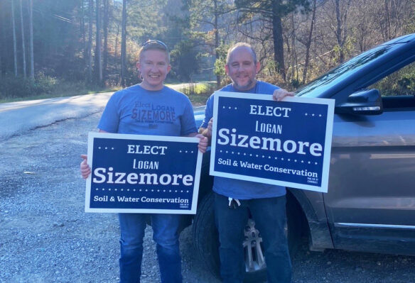 Picture of Logan Sizemore holding an "Elect Logan Sizemore" sign with his uncle, who is holding a similar sign, on election night 2022.
