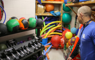 A teacher looks into a closet full of gym supplies.