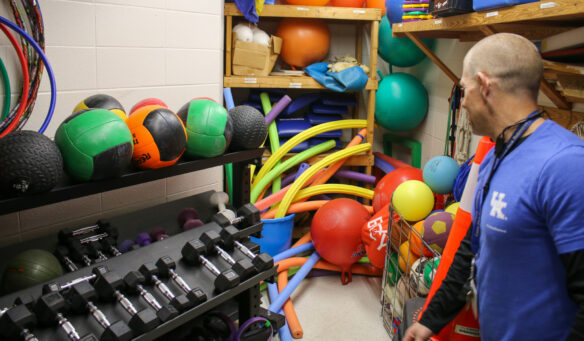 A teacher looks into a closet full of gym supplies.