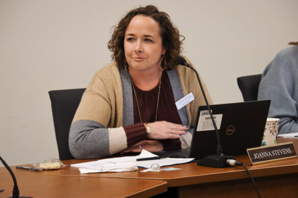 A woman speaks as she sits at a desk