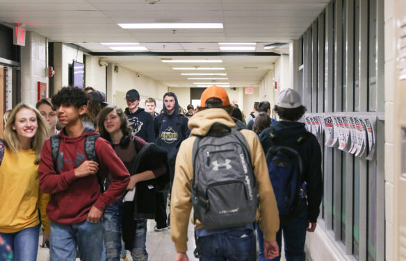 A picture of high school students walking down a school hallway between classes.