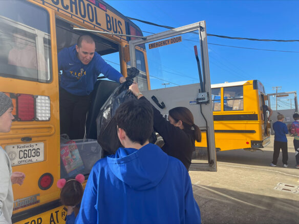 A man standing in the back of a bus hands out a bag to someone outside the bus