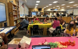 A group of women sit around a table in a room filled with bookcases