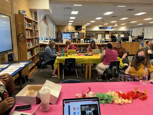 A group of women sit around a table in a room filled with bookcases