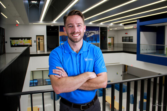 A man stands with his arms crossed and smiles