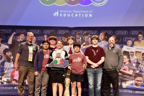 Photo Of A Group Of Six Students On Stage Holding An Stlp Trophy, Standing Next To Two Kentucky Department Of Education Employees.