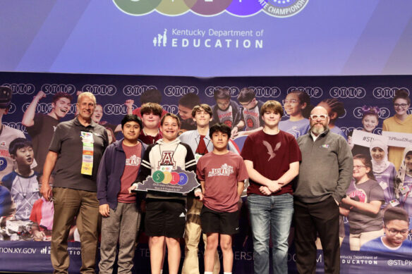 Picture of a group of six students on stage holding an STLP trophy, standing beside two Kentucky Department of Education staff members.