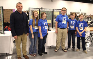 Picture of Jason Glass standing in front of a project board next to students from 6th-grade students from Austin Tracy Elementary School in Barren County.