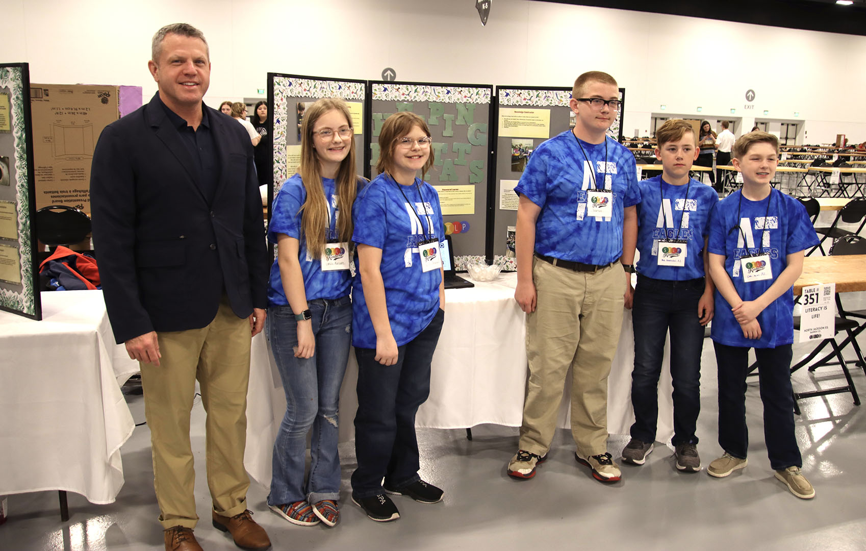 Picture of Jason Glass standing in front of a project board next to students from 6th-grade students from Austin Tracy Elementary School in Barren County.
