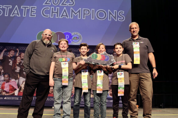 Picture of a group of four young students on stage holding an STLP trophy, standing beside two Kentucky Department of Education staff members.