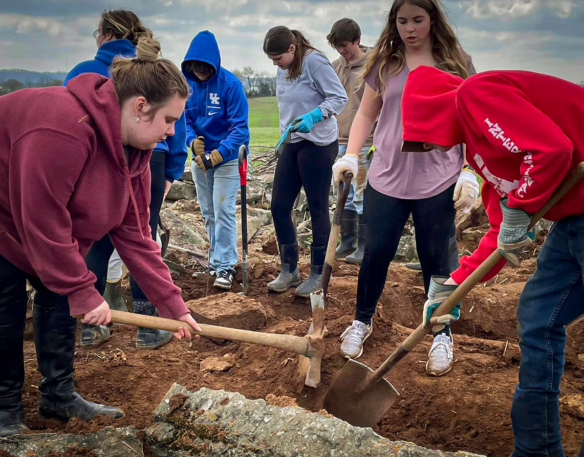 A group of students dig up old headstones in a cemetery