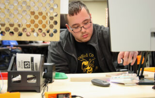 A man uses tools at a desk