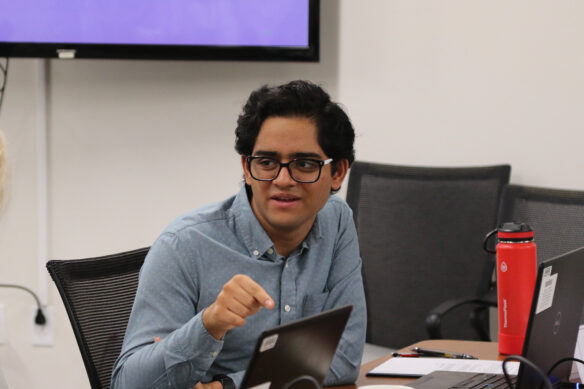 A man points down at a table as he speaks