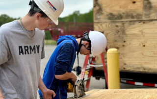 Picture of two students in hard hats working on a tiny house.