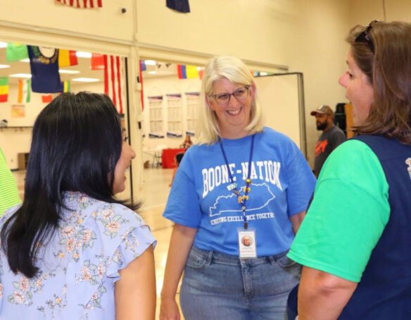 Picture of Julie Pile smiling and talking to two women in a school hallway.